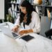 Ethnic lady working remotely on netbook at table in room | IBOMMA TV